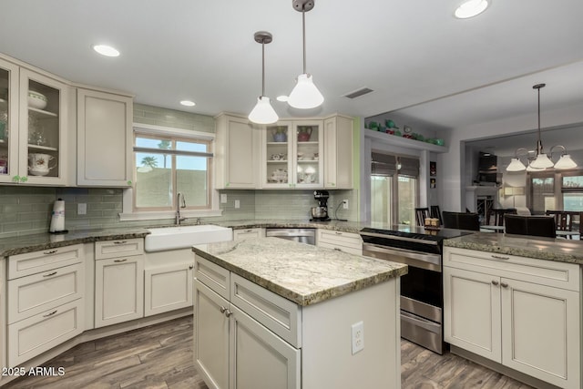 kitchen featuring decorative light fixtures, a center island, sink, and stainless steel electric range