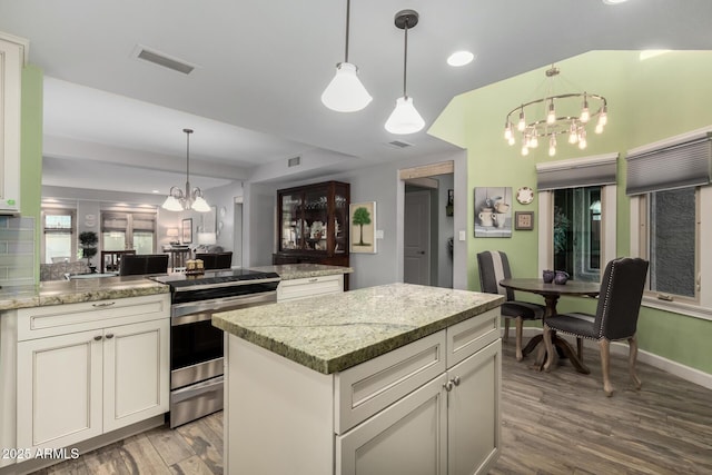 kitchen with pendant lighting, light stone countertops, a center island, and stainless steel electric range oven