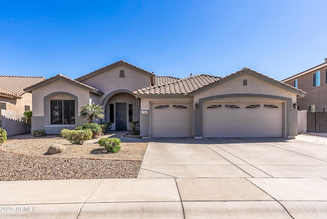 mediterranean / spanish-style home featuring stucco siding, fence, concrete driveway, a garage, and a tiled roof