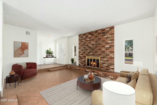 living room featuring visible vents, a fireplace, a textured ceiling, and light tile patterned floors