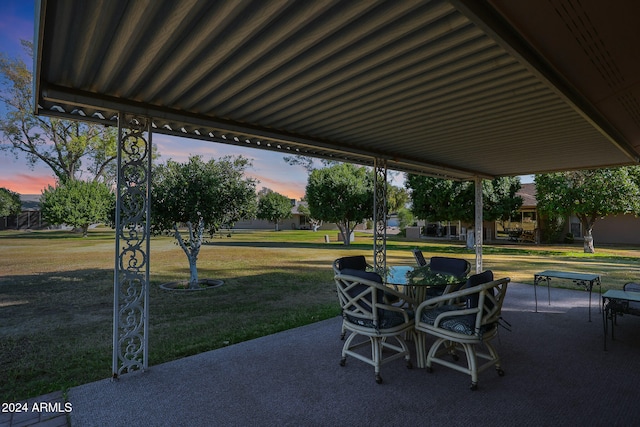 patio terrace at dusk featuring a yard