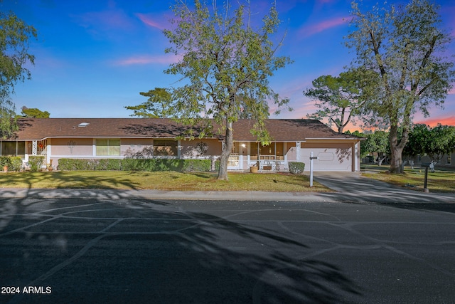 ranch-style home featuring a garage and a lawn