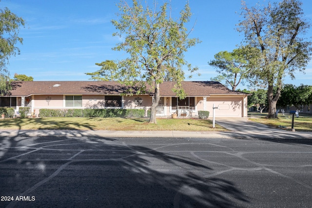 ranch-style house featuring a front yard, a garage, and a porch