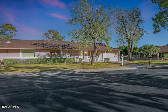 ranch-style house with a garage and a lawn