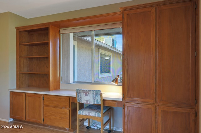 unfurnished office featuring built in desk and light wood-type flooring