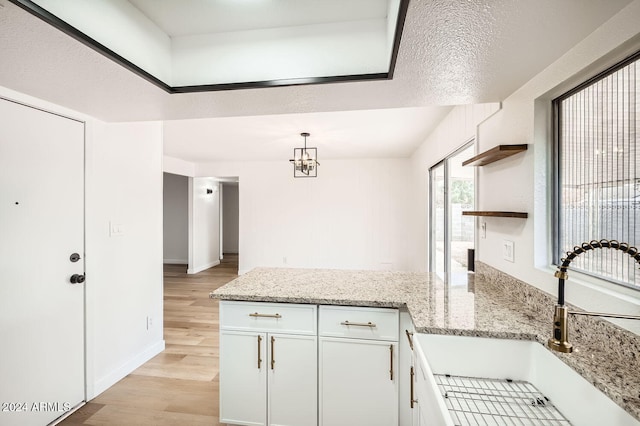 kitchen featuring light hardwood / wood-style floors, light stone counters, a textured ceiling, sink, and white cabinetry