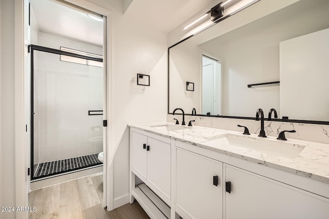 bathroom featuring hardwood / wood-style floors, a shower with door, vanity, and toilet