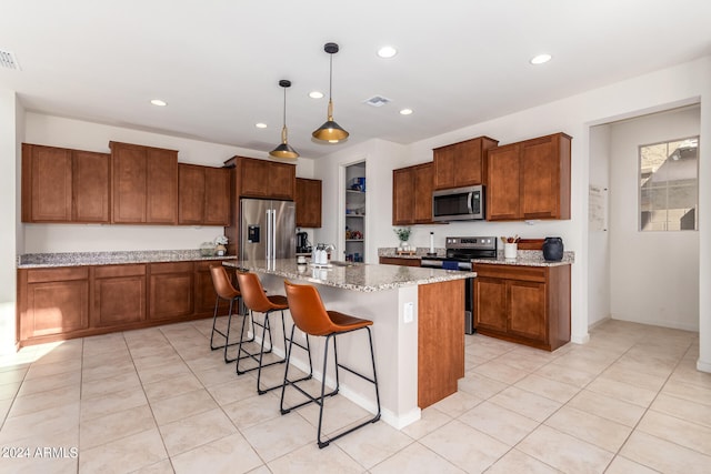 kitchen featuring light stone counters, a kitchen island with sink, hanging light fixtures, a breakfast bar area, and appliances with stainless steel finishes