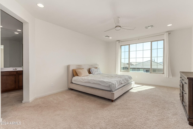 bedroom featuring light colored carpet, ensuite bathroom, and ceiling fan