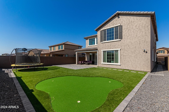 rear view of house featuring a trampoline and a patio