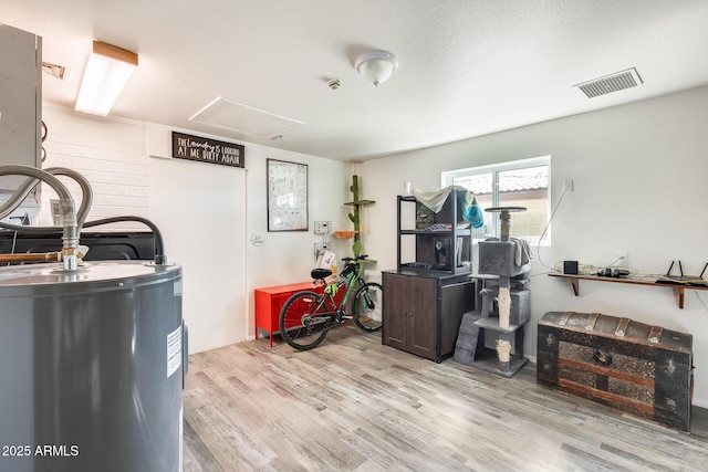 miscellaneous room with water heater and light wood-type flooring