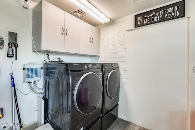 laundry room with hardwood / wood-style flooring, cabinets, and washing machine and clothes dryer