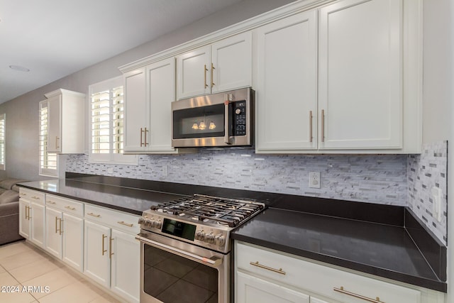 kitchen with white cabinets, light tile patterned floors, backsplash, and appliances with stainless steel finishes