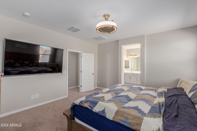 bedroom with ensuite bathroom and light carpet