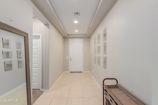 corridor with light tile patterned floors and a tray ceiling