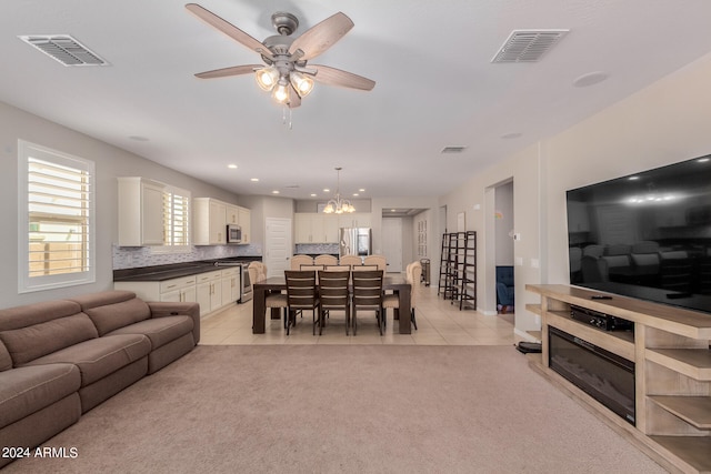 living room with light carpet and ceiling fan with notable chandelier