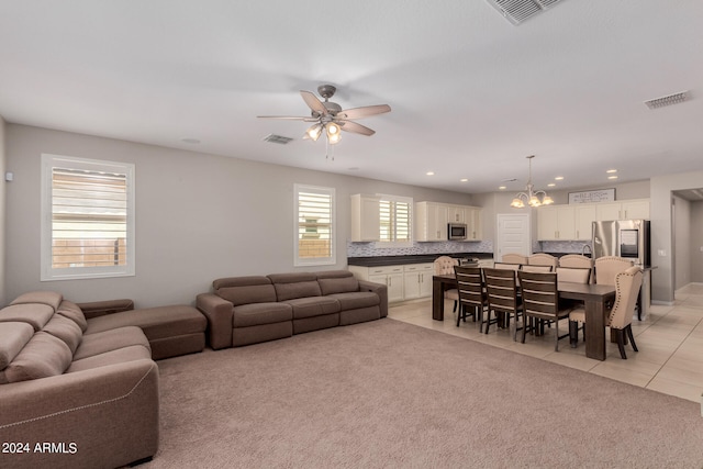 living room featuring light tile patterned floors, ceiling fan with notable chandelier, and a wealth of natural light