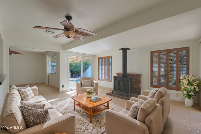 living room featuring a wood stove, light tile patterned floors, and ceiling fan