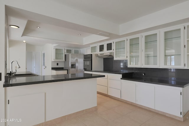 kitchen featuring black appliances, backsplash, sink, white cabinets, and a tray ceiling