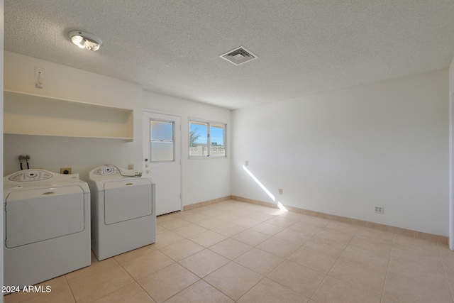 laundry room featuring a textured ceiling, washer and clothes dryer, and light tile patterned flooring