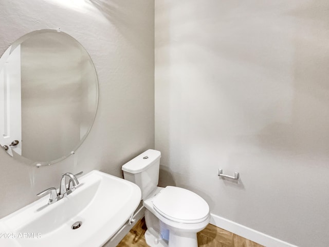 bathroom featuring toilet, parquet floors, and sink