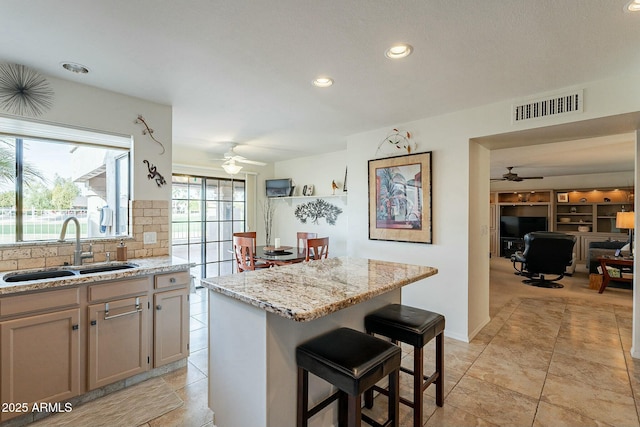 kitchen featuring a kitchen breakfast bar, a center island, ceiling fan, and sink