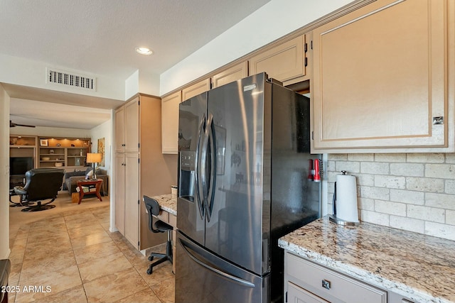 kitchen with backsplash, light stone counters, light tile patterned floors, and stainless steel refrigerator with ice dispenser