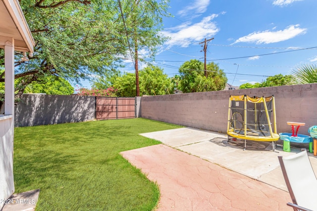 view of yard featuring a trampoline, a patio area, and a fenced backyard