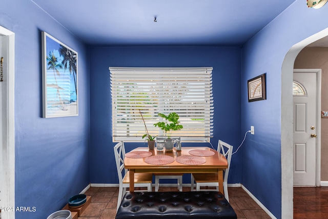 tiled dining room with arched walkways and baseboards