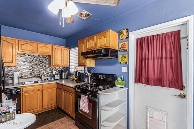 kitchen featuring under cabinet range hood, a sink, light countertops, black appliances, and tasteful backsplash