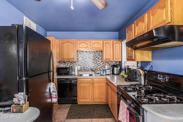 kitchen with under cabinet range hood, a sink, light countertops, black appliances, and tasteful backsplash