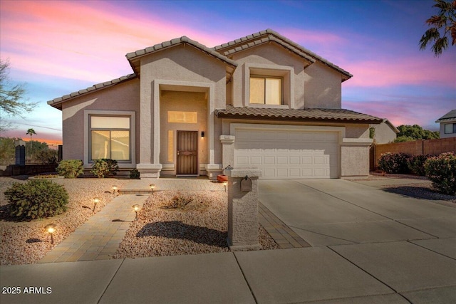 mediterranean / spanish home featuring driveway, an attached garage, fence, and stucco siding