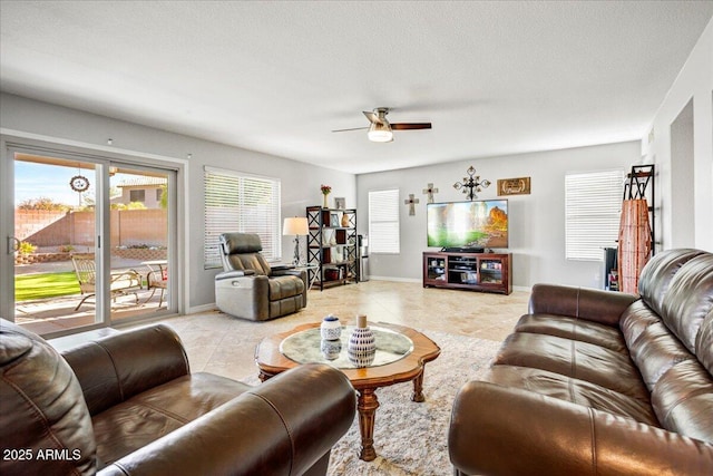 living room featuring light tile patterned floors, a textured ceiling, a ceiling fan, and baseboards