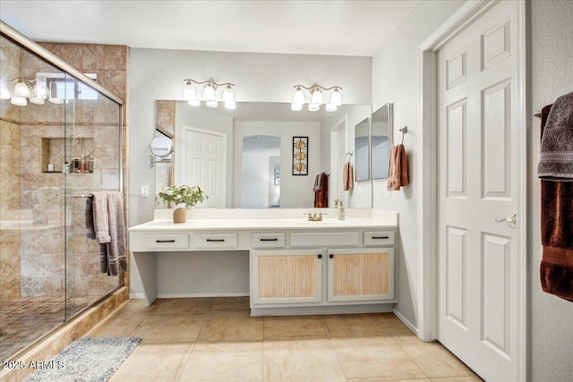 full bathroom with a stall shower, vanity, baseboards, and tile patterned floors