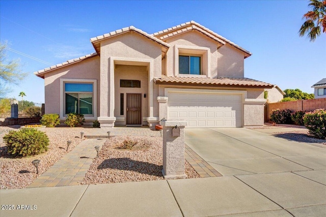 mediterranean / spanish-style home featuring a garage, fence, concrete driveway, and stucco siding