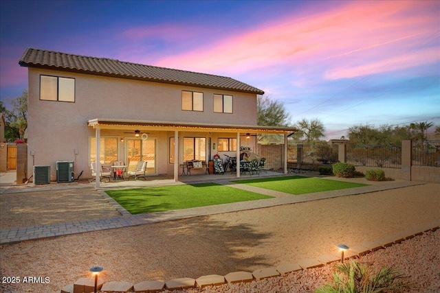 rear view of house featuring a patio area, fence, central AC, and stucco siding