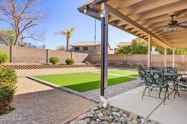 view of patio featuring outdoor dining space, a fenced backyard, and a ceiling fan