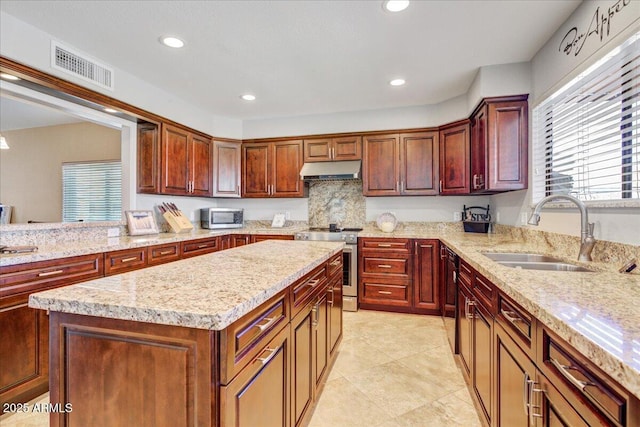 kitchen with recessed lighting, under cabinet range hood, a sink, visible vents, and stainless steel range oven