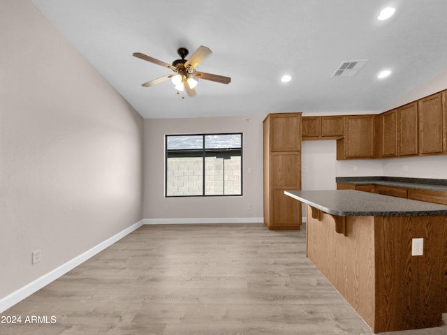 kitchen featuring ceiling fan, light wood-type flooring, and a breakfast bar area