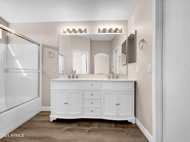 bathroom featuring vanity, wood-type flooring, and shower / bath combination with glass door