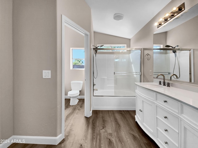 full bathroom with bath / shower combo with glass door, lofted ceiling, toilet, vanity, and hardwood / wood-style flooring