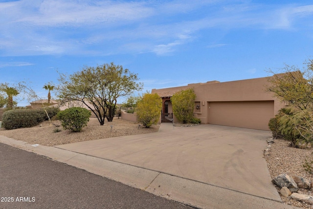 adobe home with driveway, a garage, and stucco siding