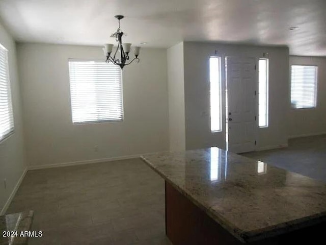 kitchen with light stone counters, a notable chandelier, and decorative light fixtures