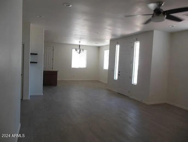 unfurnished room featuring ceiling fan with notable chandelier and dark wood-type flooring