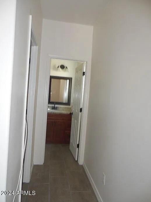 hall featuring dark tile patterned floors and sink