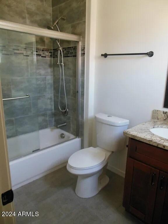 full bathroom featuring toilet, bath / shower combo with glass door, and vanity