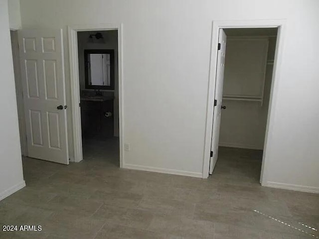 unfurnished bedroom with ensuite bath, a walk in closet, and a closet