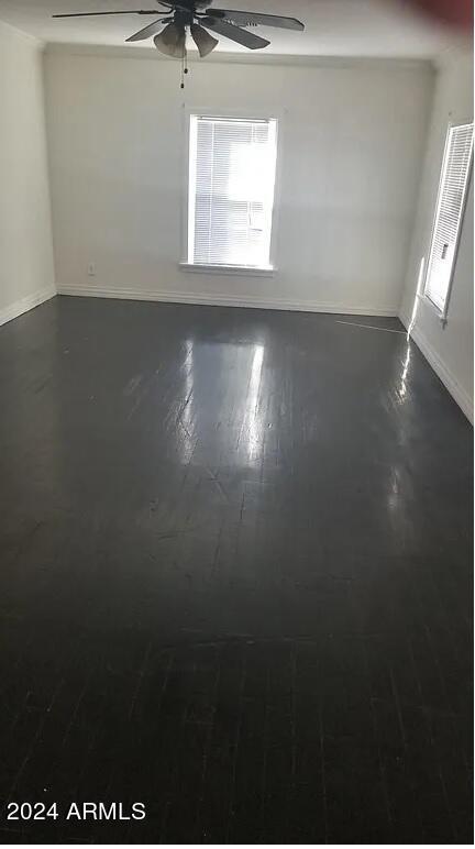 unfurnished room with dark wood-type flooring and ceiling fan