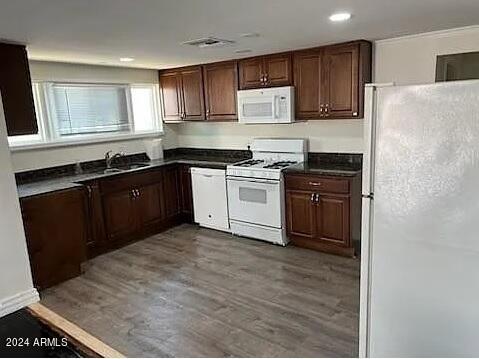 kitchen featuring white appliances, sink, dark brown cabinetry, and dark hardwood / wood-style floors