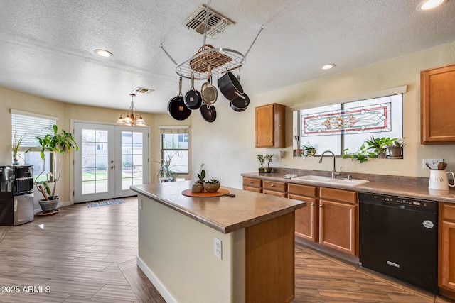 kitchen with pendant lighting, dishwasher, a center island, french doors, and sink